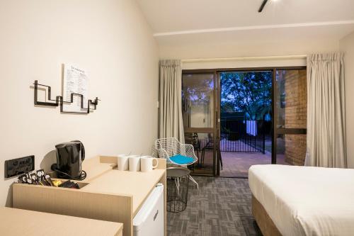 a hotel room with a bed and a desk and a kitchen at Nightcap at Kawana Waters Hotel in Kawana Waters