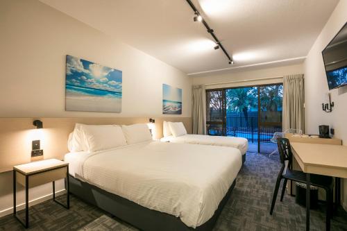 a hotel room with a bed and a desk and a window at Nightcap at Kawana Waters Hotel in Kawana Waters