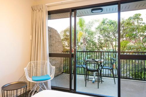 a room with a balcony with chairs and a table at Nightcap at Kawana Waters Hotel in Kawana Waters