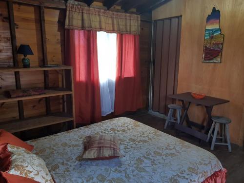 a bedroom with a bed and a table and a window at Los Nogales in Punta Del Diablo