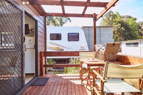 eine Terrasse mit einem Tisch, Stühlen und einem Anhänger in der Unterkunft Lorne Foreshore Caravan Park in Lorne