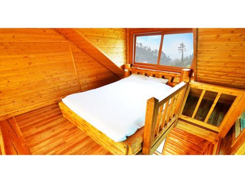 1 dormitorio con 1 cama en una cabaña de madera en Attene Pension, en Jeju