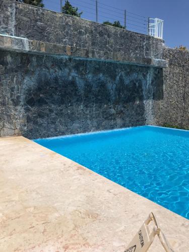 a pool with a chair next to a stone wall at Vista Mare Spectacular Ocean View Top Floor 1-Bedroom Condo, Samana in Santa Bárbara de Samaná