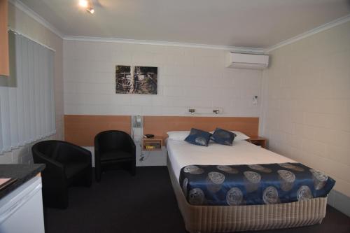 ein Hotelzimmer mit einem Bett und zwei Stühlen in der Unterkunft Mundubbera Billabong Motor Inn in Mundubbera