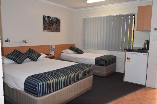 a hotel room with two beds and a television at Mundubbera Billabong Motor Inn in Mundubbera