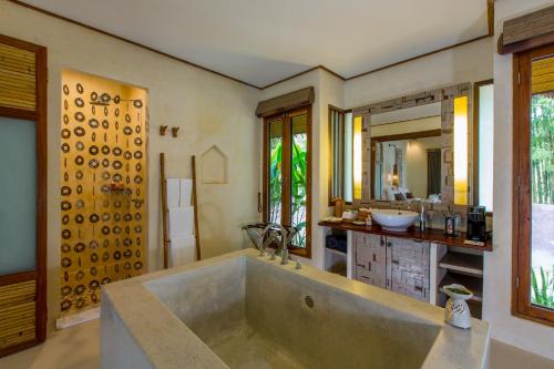 a bathroom with a tub, sink, mirror and bathtub at Bangsak Village - Adults Only - SHA Extra Plus in Khao Lak