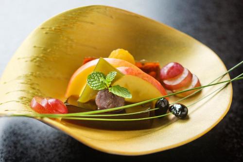 a gold bowl filled with fruit on a plate at Ryokan KANADE in Kyoto