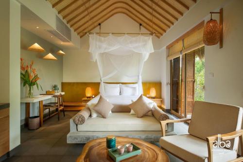 a living room with a bed and a table at Alba Wellness Resort By Fusion in Hue