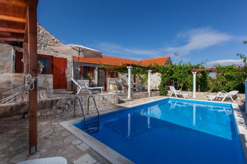 a swimming pool with an umbrella next to a house at Countryside Family Villa with Private Pool in Donje Selo na Šolti