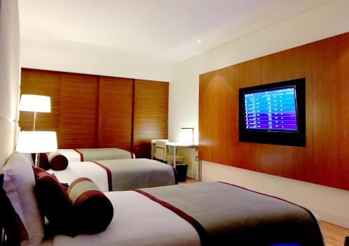 a hotel room with two beds and a flat screen tv at Oryx Airport Hotel -Transit Only in Doha