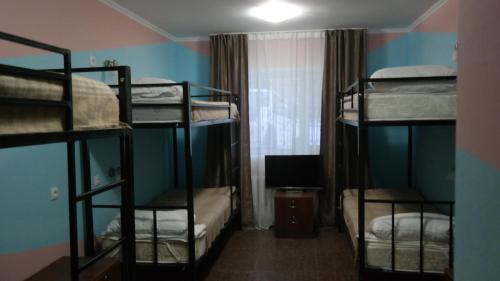 a room with three bunk beds and a television at Astana Best Hostel in Astana