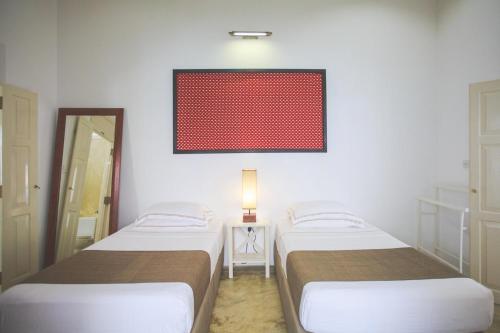 two beds in a room with a red painting on the wall at Karmel Villa Thalduwa Island - Five Bedroom Luxury Villa with Private Pool in Ahangama