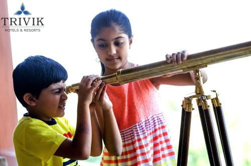 a young boy and a girl looking at a telescope at Trivik Hotels & Resorts, Chikmagalur in Chikmagalūr