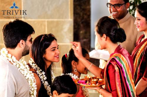 a group of people standing around a woman holding a plate of food at Trivik Hotels & Resorts, Chikmagalur in Chikmagalūr