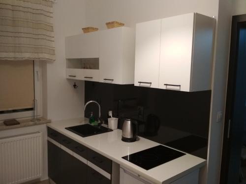 a small kitchen with white cabinets and a sink at Apartament Scorpion Modlin in Czosnów