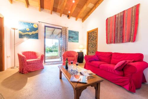 a living room with a red couch and two chairs at Agroturisme s' Horta in Capdepera