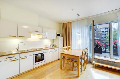 uma cozinha com armários brancos e uma mesa de madeira com cadeiras em Apartment24 - Foorum em Talin