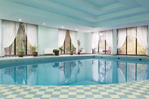 a swimming pool in a room with windows at Ramada by Wyndham Tashkent in Tashkent