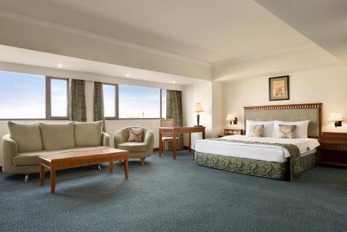 a hotel room with a bed and a couch and chairs at Ramada by Wyndham Tashkent in Tashkent