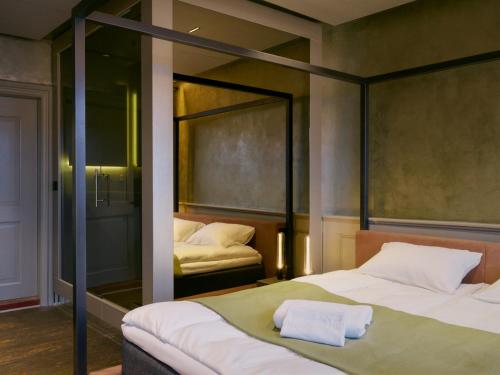 a bedroom with two beds and a mirror at Tollboden Hotell - Unike Hoteller in Kragerø