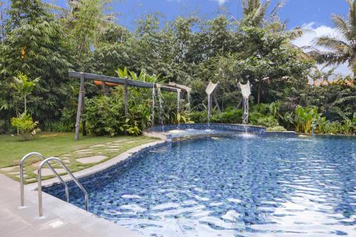 a large swimming pool in a yard with trees at Purple Palms Resort & Spa in Kushālnagar