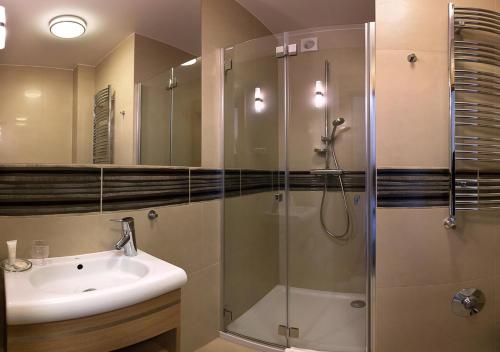 a bathroom with a glass shower and a sink at Hotel KARO in Radom