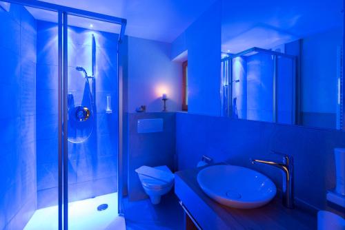 a blue bathroom with a shower and a toilet and a sink at Der Berghof in Alpbach