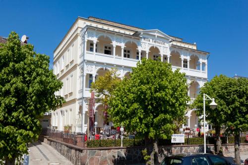 ein weißes Gebäude mit Bäumen davor in der Unterkunft Villa Fernsicht - Apt. 10 in Ostseebad Sellin