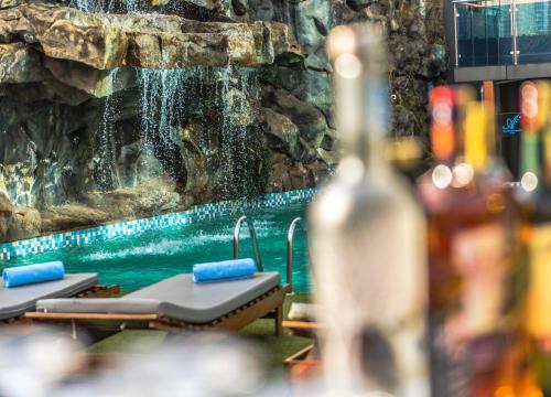a waterfall in a pool with chaise lounges and a bottle of wine at PrideInn Azure Hotel Nairobi Westlands in Nairobi