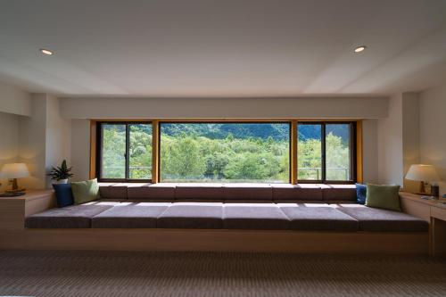 a large couch in a room with a large window at Kamikochi Lemeiesta Hotel in Matsumoto