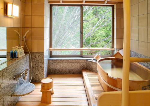 a bathroom with a large window and a tub at Kamikochi Lemeiesta Hotel in Matsumoto
