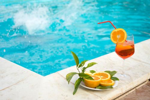 ein Glas Orangensaft neben einem Pool in der Unterkunft Sicily Country House & Beach in Catania