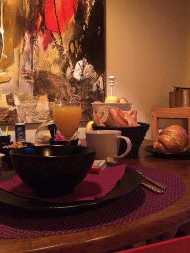- une table avec un bol de nourriture et un verre de jus d'orange dans l'établissement Les Sittelles de Bamboche, à Saint-Symphorien-sur-Coise