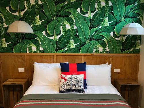 a bedroom with a bed with a wall of leaves at Boogie Woogie Beach House in Old Bar