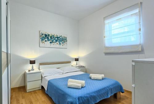 a white bedroom with a blue bed and a window at Sweet Home Apartment Split in Split