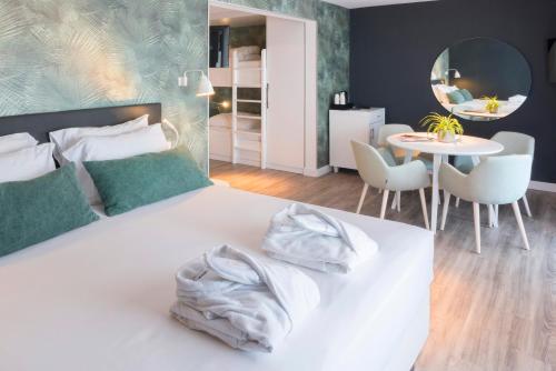 a bedroom with a white bed with a table and chairs at Van der Valk Hotel Saint-Aygulf in Saint-Aygulf