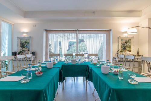 a room with long tables with green table cloths at Il San Francesco Charming Hotel in Sabaudia