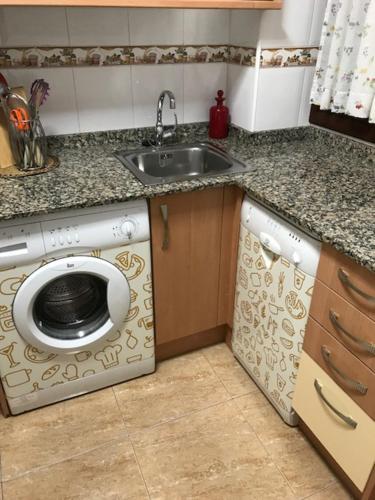 a kitchen with a sink and a washing machine at Apartamentos Costa Noja in Noja