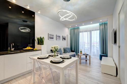 a kitchen and living room with a white table and chairs at Live & Travel Apartments Number 1 in Gdańsk