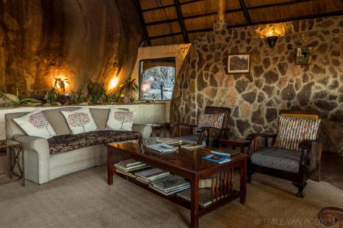 a living room with a couch and two chairs and a table at Big Cave Camp in Matopos