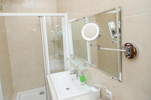 La salle de bains est pourvue d'une douche, d'un lavabo et d'un miroir. dans l'établissement M&M Aparthotel VIP, à Soumy
