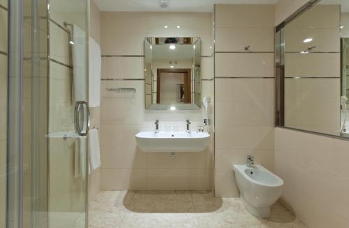 a bathroom with a sink and a mirror and a toilet at Gran Hotel Corona Sol in Salamanca