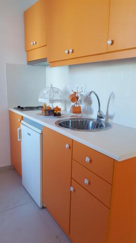 a kitchen with orange cabinets and a sink at Studio Lefaki in Rethymno Town