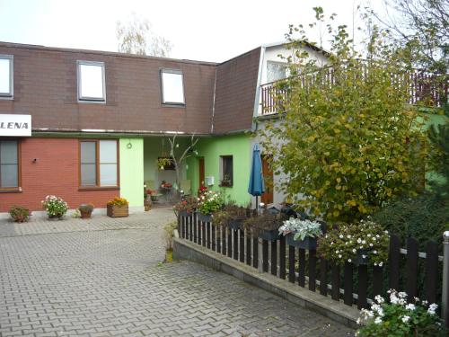 a building with a fence and flowers in front of it at Apartments - Penzion Lena in Hradec Králové
