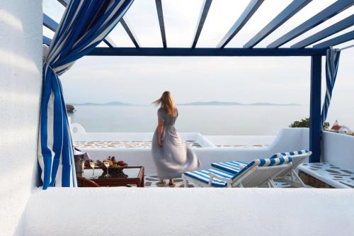 a woman in a wedding dress standing on a balcony overlooking the ocean at San Marco Hotel and Villas in Houlakia