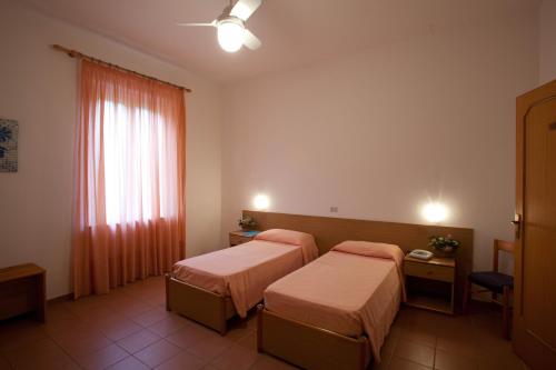 a hotel room with two beds and a window at Hotel Moderno in Guardia Piemontese Terme