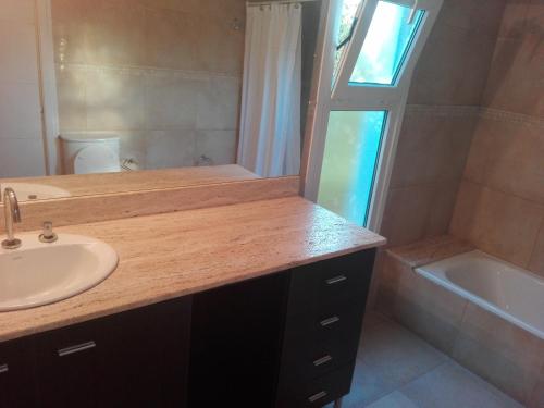 een badkamer met een wastafel, een spiegel en een bad bij Hosteria Ruphay in Tandil
