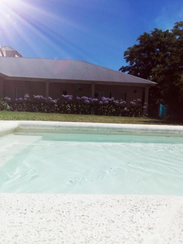a swimming pool in front of a house with purple flowers at Hosteria Ruphay in Tandil