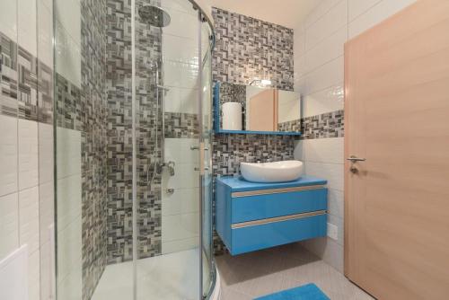 a bathroom with a blue sink and a glass shower at Crowonder Luxury Vir- 6 New Apartments for Families with Playground for Kids in Vir
