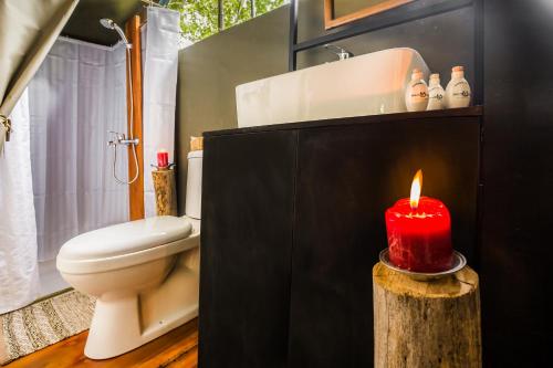 a bathroom with a red candle on a log at Mahoora Wilpattu - by Eco Team in Wilpattu